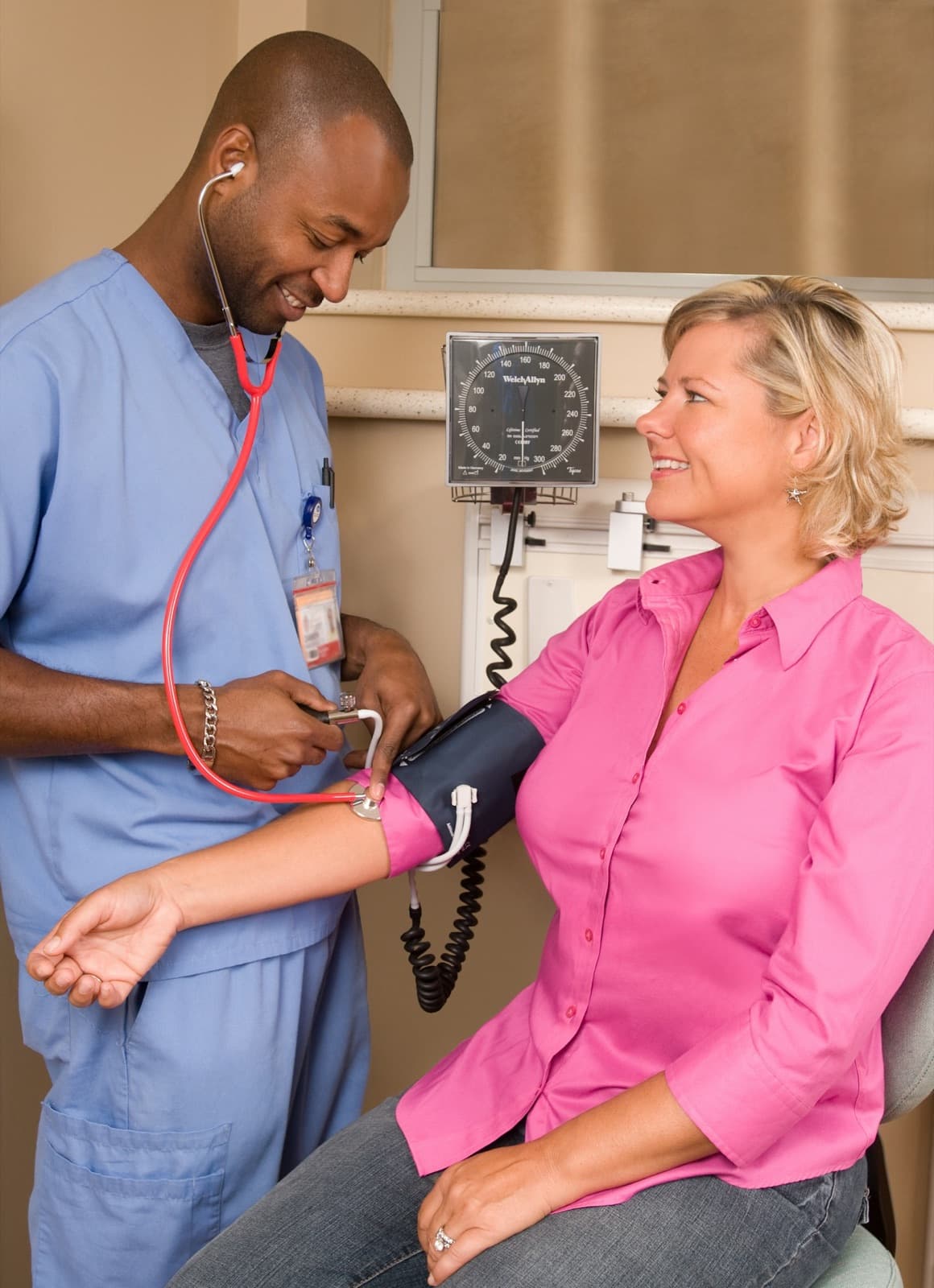 A nurse checking a smiling patient's blood pressure